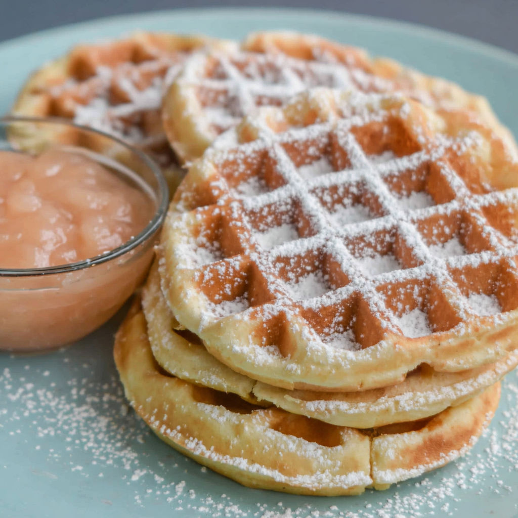 A plate of waffles with powdered sugar on top.