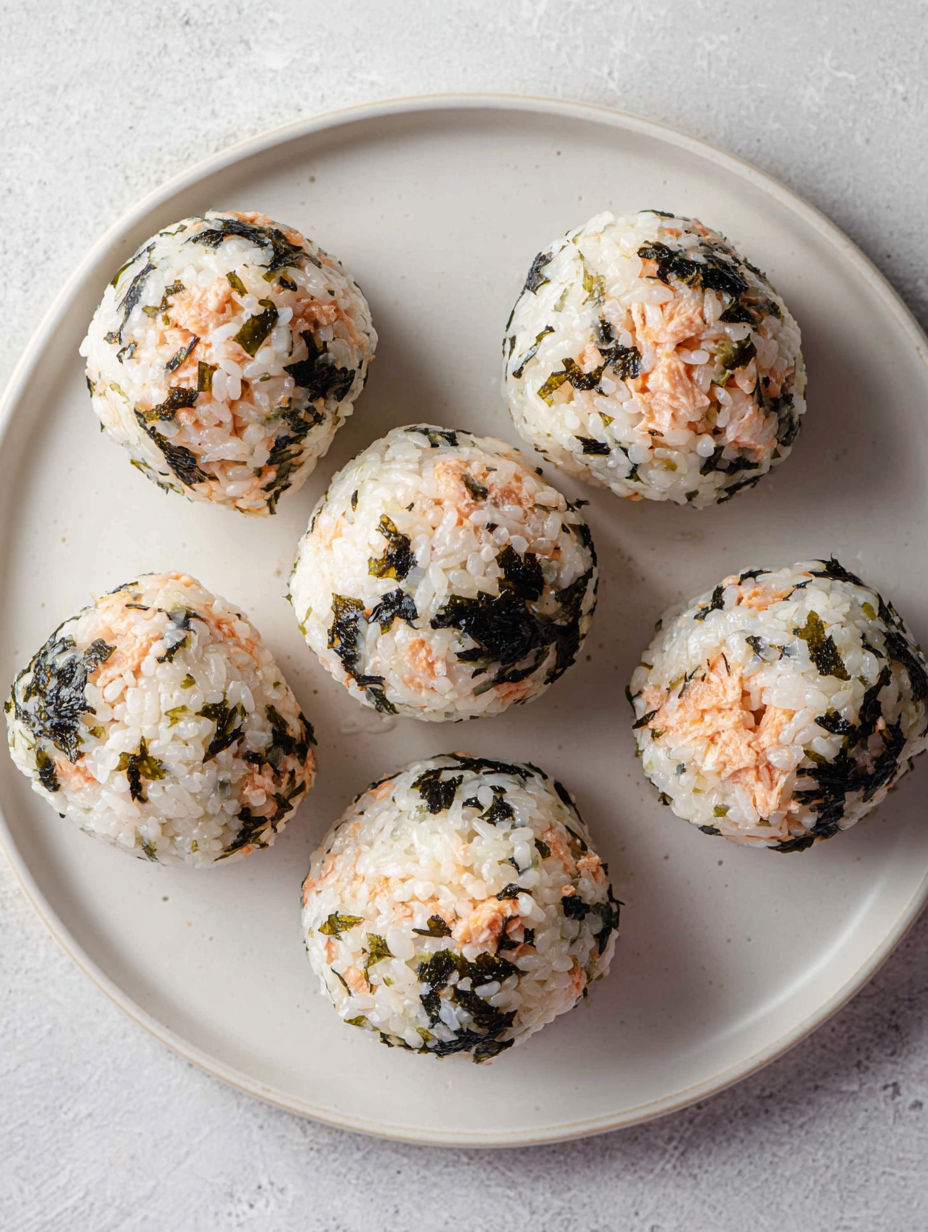 A plate of rice balls with seaweed.