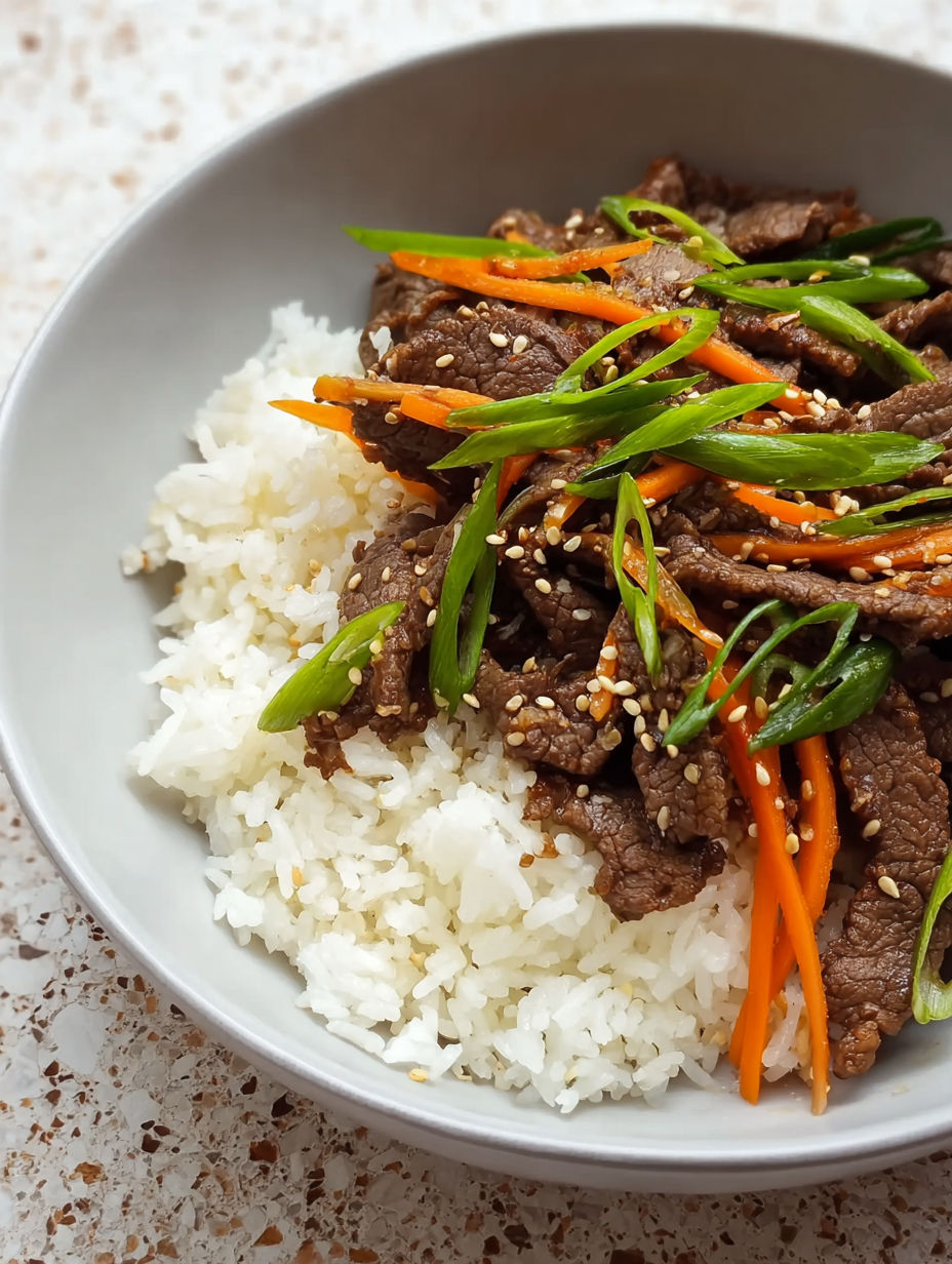 A bowl of beef bulgogi with rice and carrots.