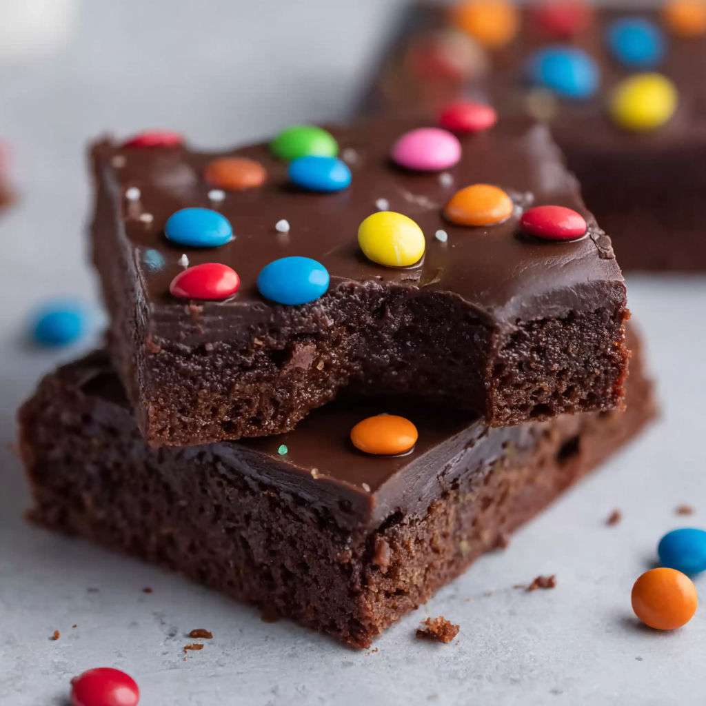 A close up of a chocolate brownie with chocolate chips and rainbow sprinkles.