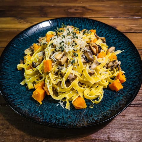 A plate of pasta with mushrooms and carrots.