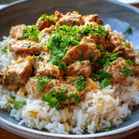 A bowl of rice with meat and sauce.