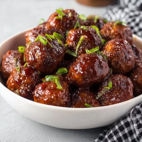 A bowl of meatballs with green toppings.