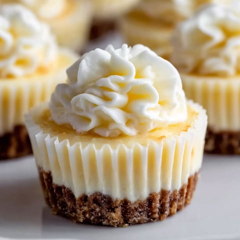 A bite size cheesecake with whipped cream on top.