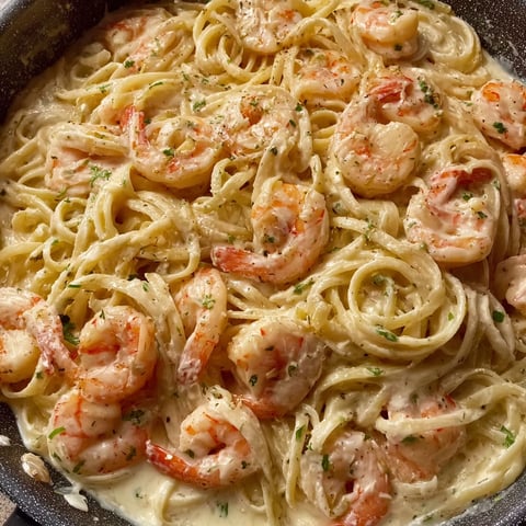 A dish of shrimp and pasta with Alfredo sauce.